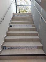 Sätze aus Grabinschriften auf Folie an den Treppenstufen als Wegweiser und Einstimmungselement, Haus 19 HSN
