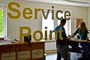 Lettering Service-Point on the glass door of the office, in the background two people