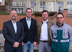 Professor Folker Flüggen, Maschinenbau-Absolvent Nico Stang und Marco Buchmann sowie Andreas Benkstein von der DEKRA vor dem Hintergrund des Audimax