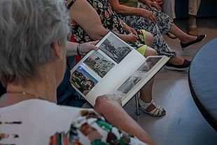 Ältere Personen schauen sich Fotos und Bücher an