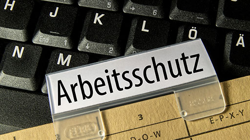 Close-up of a file folder with the tab "Occupational Health and Safety", below a section of a computer keyboard