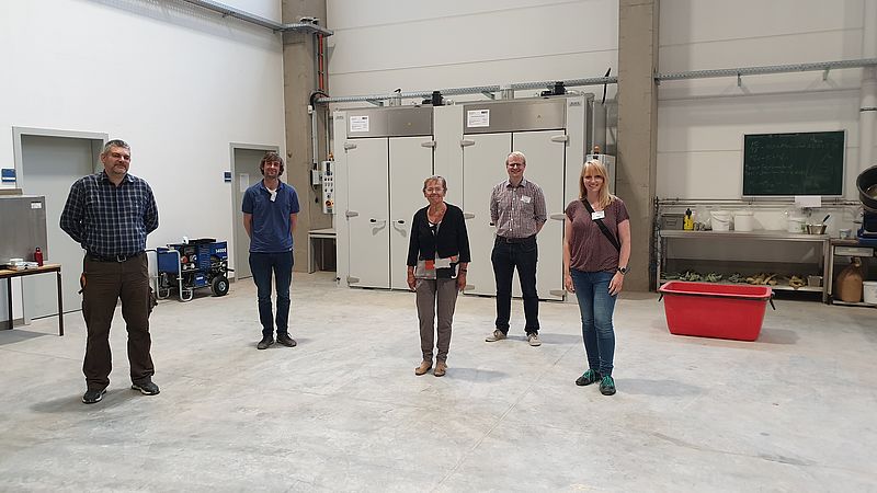 A research team from Nordhausen University of Applied Sciences stands in a test hall with technical equipment for a project on the processing and utilisation of recyclable materials.