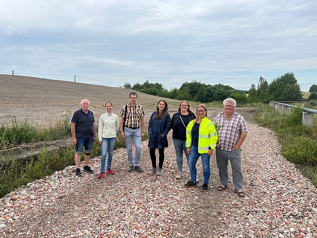 A group of people are standing on a gravel road.