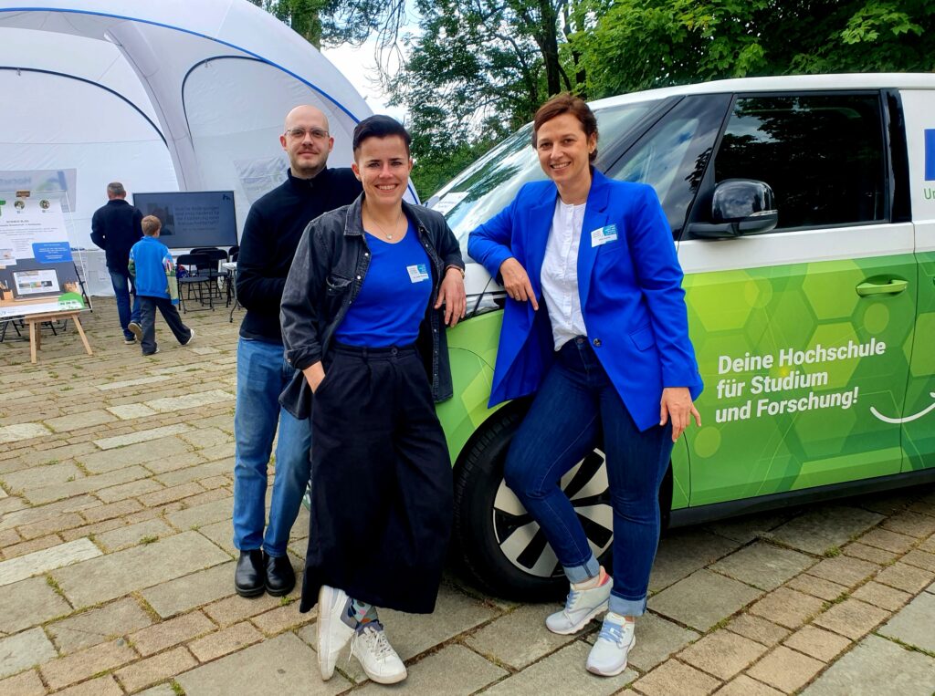 Three people in front of a car.