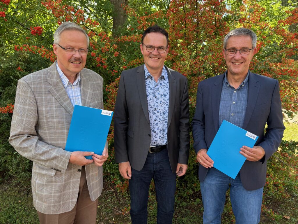 Drei Männer mit blauen Ordnern.