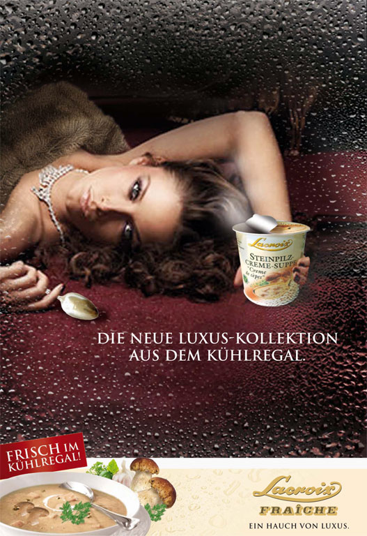 Das Motiv ist durch eine mit Wassertropfen beschlagene Glasscheibe hindurch fotografiert, was eine Kühlregal-Atmosphäre erzeugt. Dahinter liegt eine Frau mit Pelzstola und Schmuck auf einem dunkelroten Untergrund; sie hält einen Becher Lacroix Steinpilz-Creme-Suppe in der Hand. Mittig im Bild steht der Text: „DIE NEUE LUXUS-KOLLEKTION AUS DEM KÜHLREGAL.“. Am unteren Rand zeigt ein weißer Balken eine servierfertige Suppenschüssel, frische Steinpilze sowie die Logos „Lacroix FRAÎCHE“ und den Slogan „EIN HAUCH VON LUXUS.“.