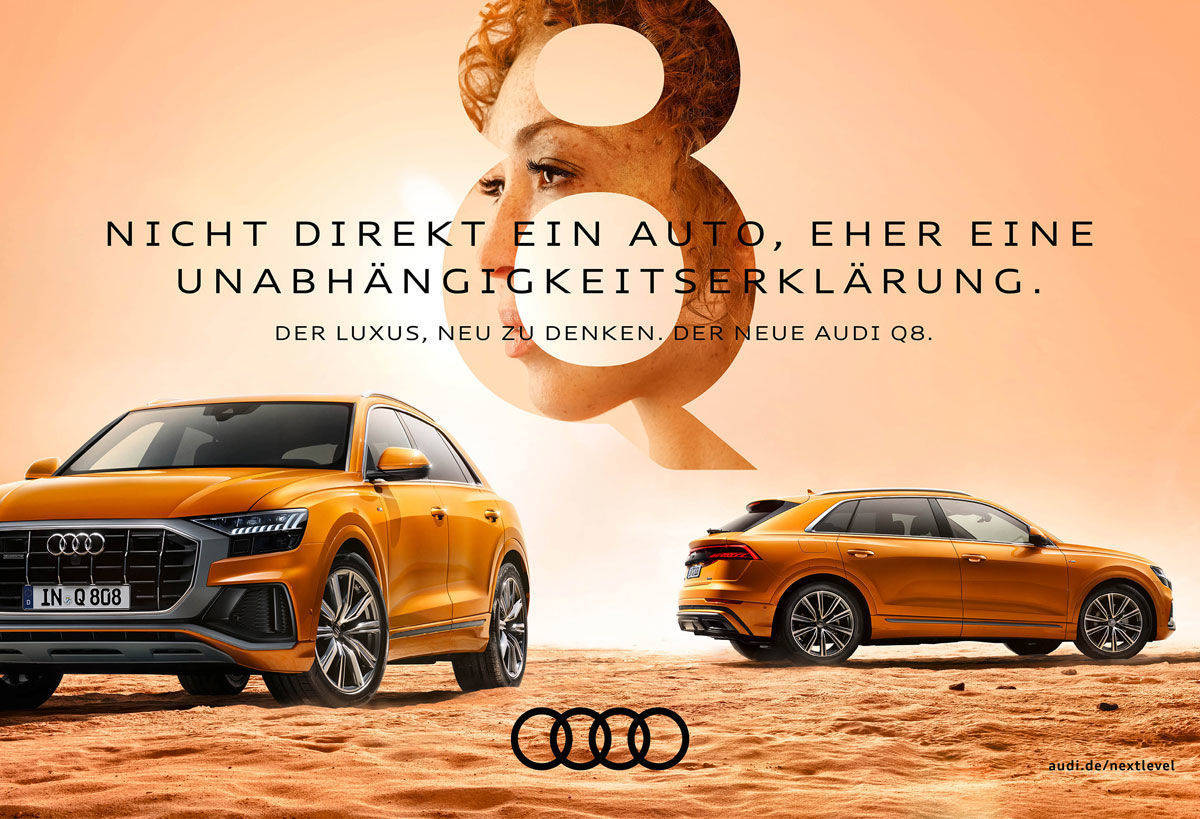 Die Anzeige zeigt zwei Perspektiven eines orange-goldenen Audi Q8 in einer sandigen Wüstenlandschaft unter einem hellen, warmen Himmel. Im Vordergrund ist die Frontpartie schräg von links zu sehen, im Hintergrund die Seiten- und Heckansicht. Zentral im oberen Bilddrittel ist eine große, transparente Ziffer „8“ platziert, in der das Porträt einer Frau im Profil erscheint. Der Text lautet: „NICHT DIREKT EIN AUTO, EHER EINE UNABHÄNGIGKEITSERKLÄRUNG. DER LUXUS, NEU ZU DENKEN. DER NEUE AUDI Q8.“