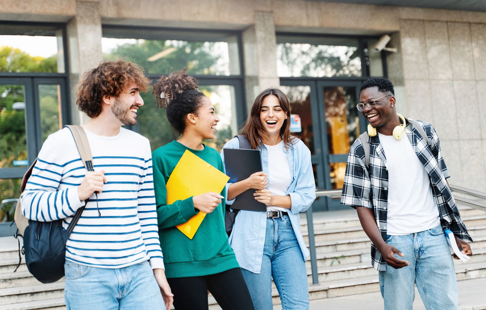 Four cheerful students in front of the building.