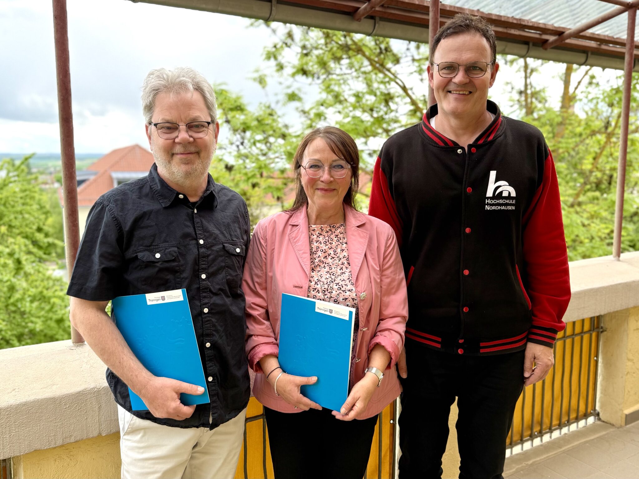 Three people with folders stand together.