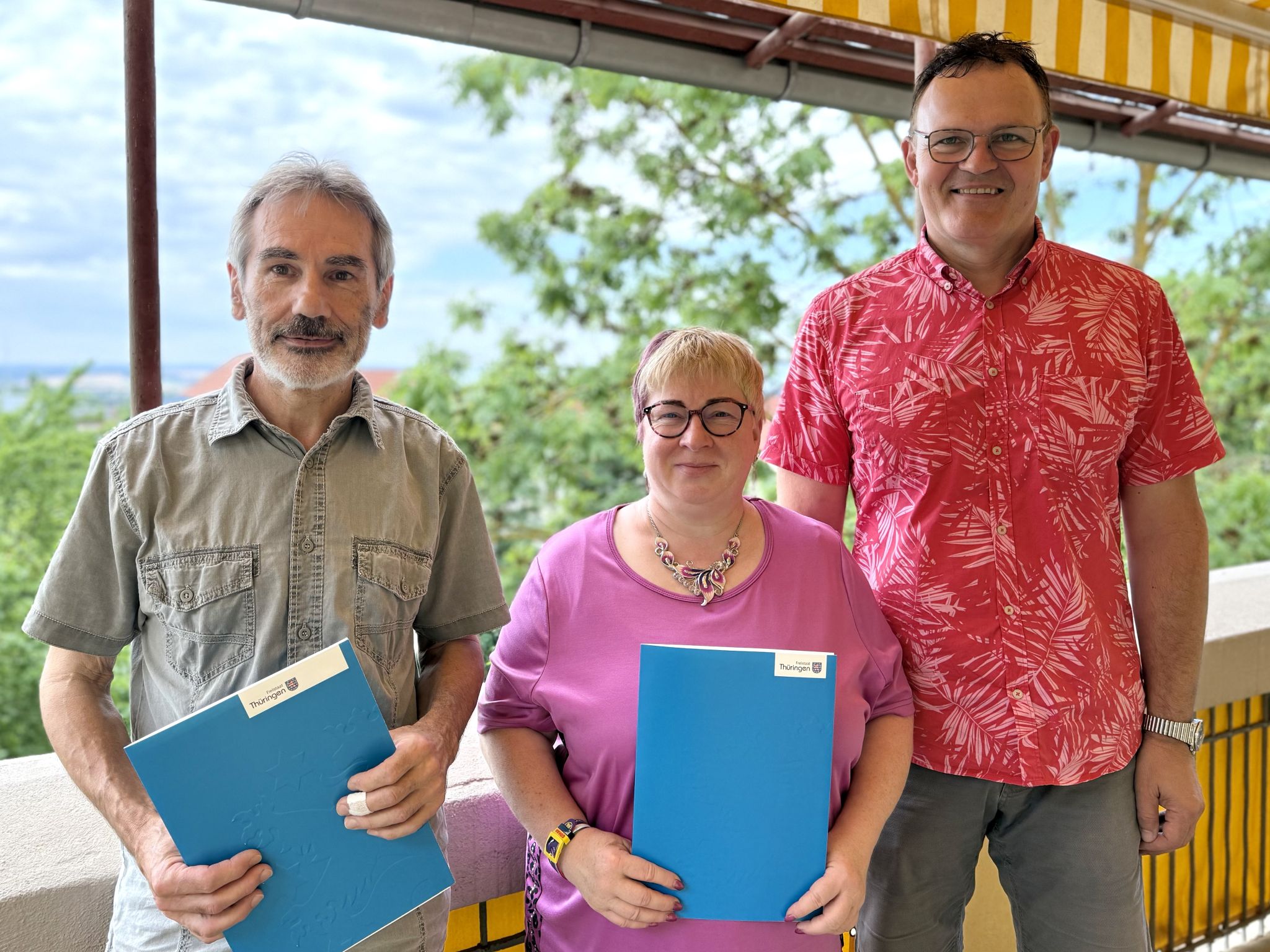 Three people carrying blue folders