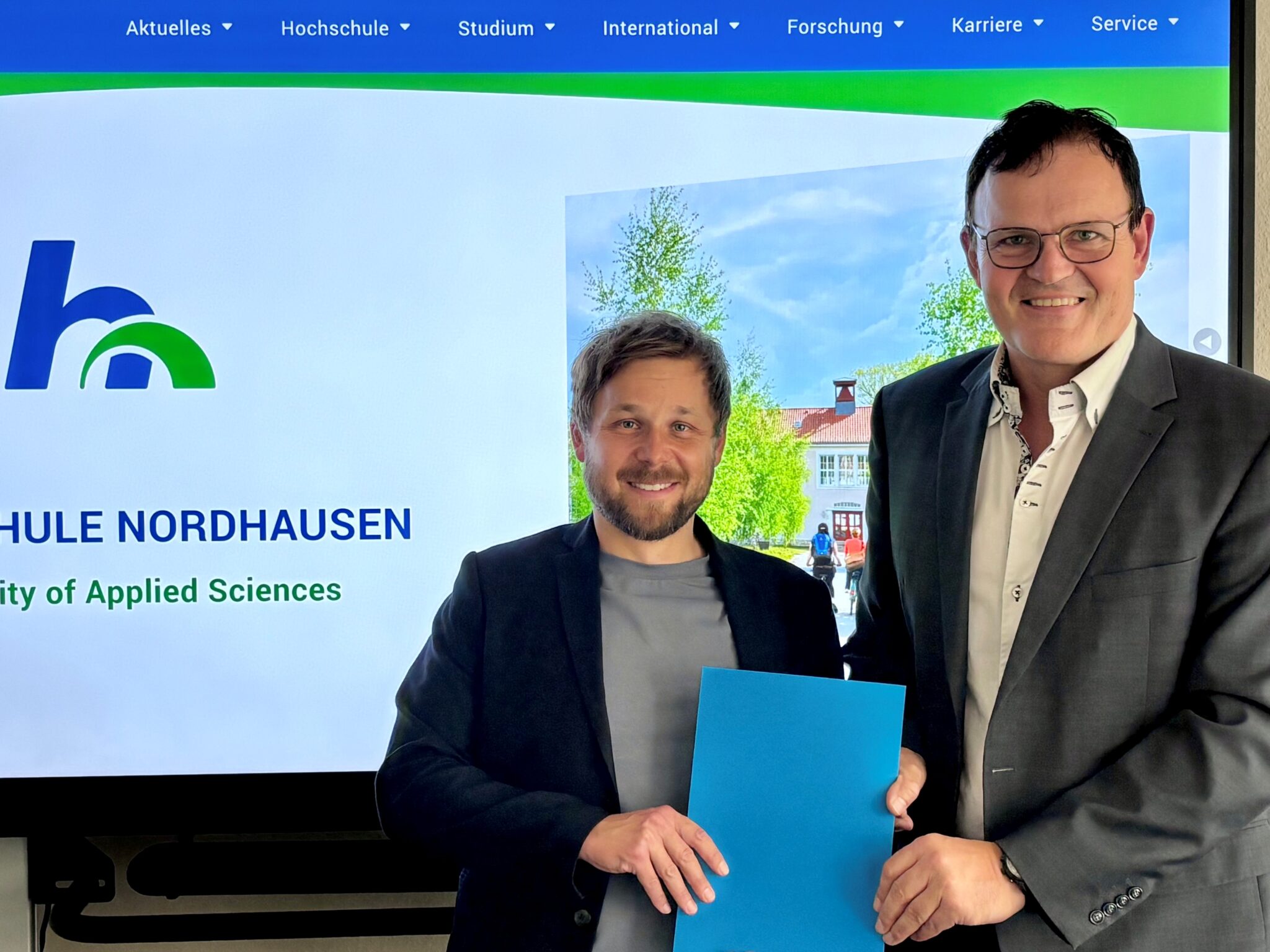 Two men with a certificate and a smile